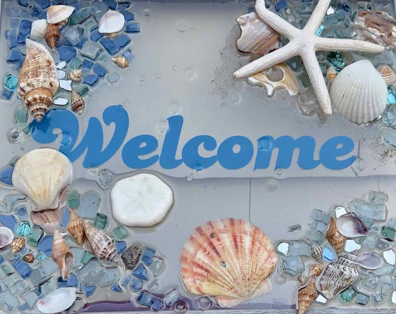 Decorative welcome sign with seashells and starfish on a blue background